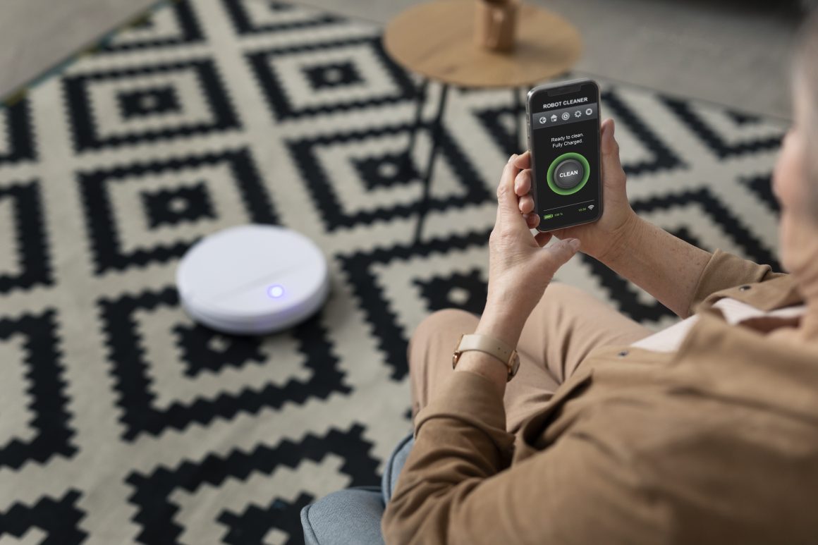 Personne contrôlant aspirateur robot via application sur tapis géométrique noir et blanc