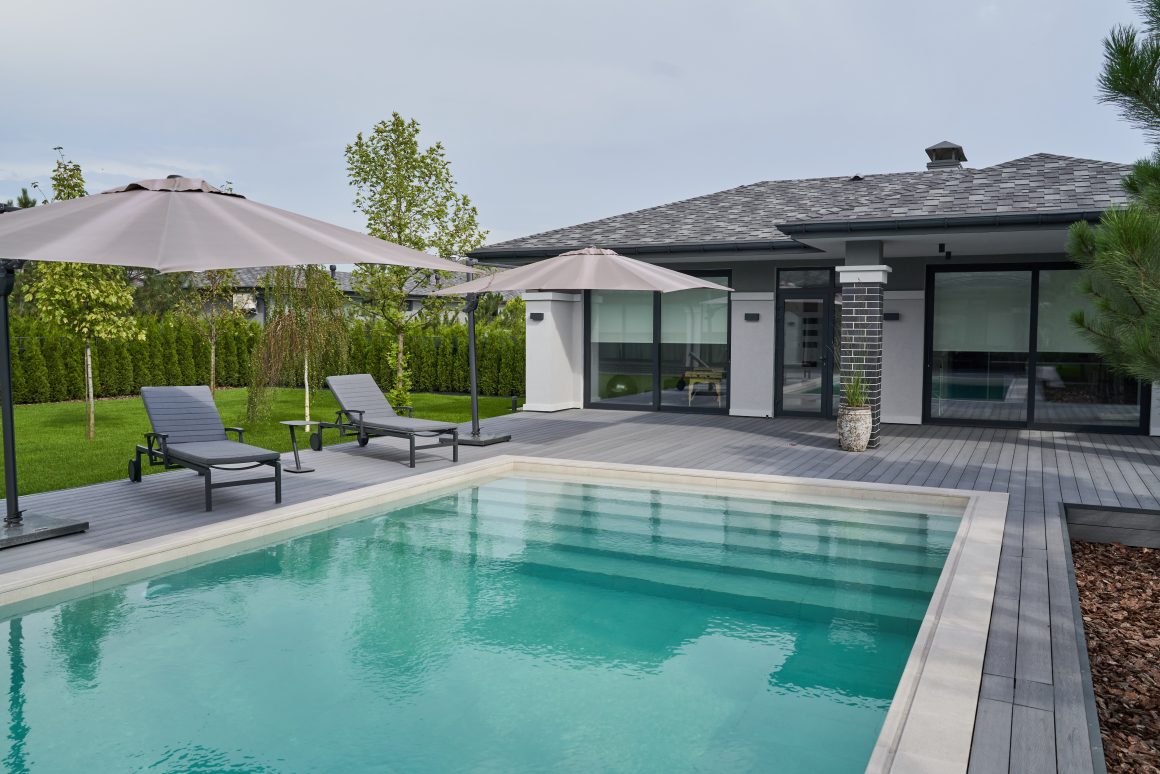 Maison moderne avec terrasse en composite, piscine , transats, parasols et jardin