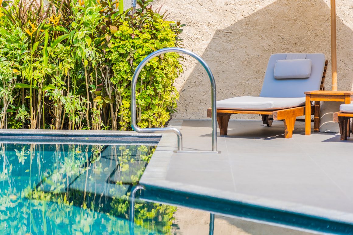 Bord de piscine ensoleillé incluant fauteuils et végétation