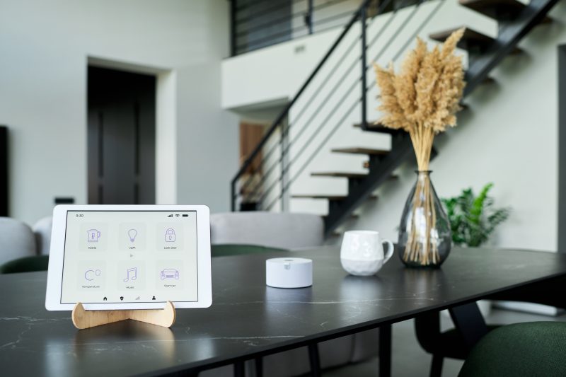 Intérieur maison domotique incluant tablette sur socle en bois, éclairage ambiant, vase pampas et table