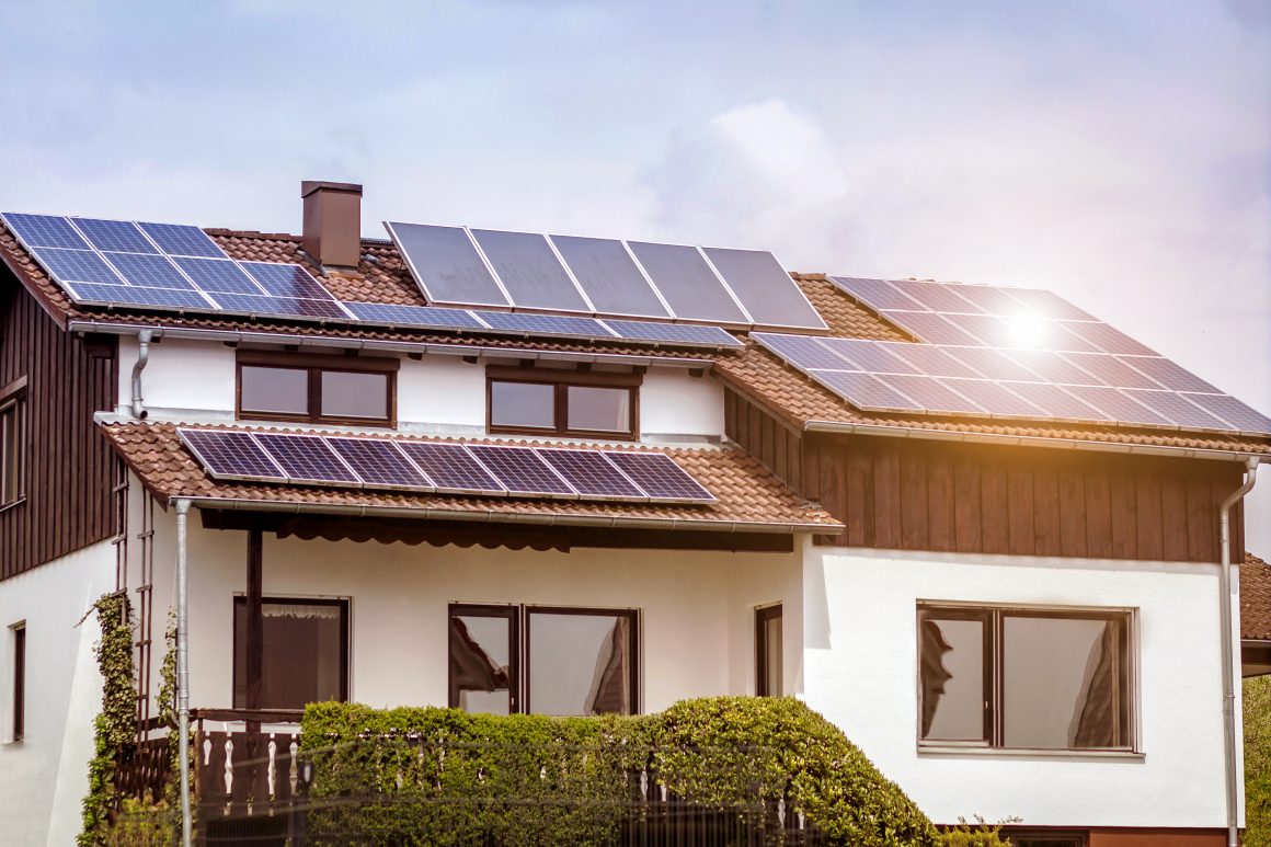 Maison moderne avec toit en tuiles, panneaux solaires, grande fenêtre et jardin soigné