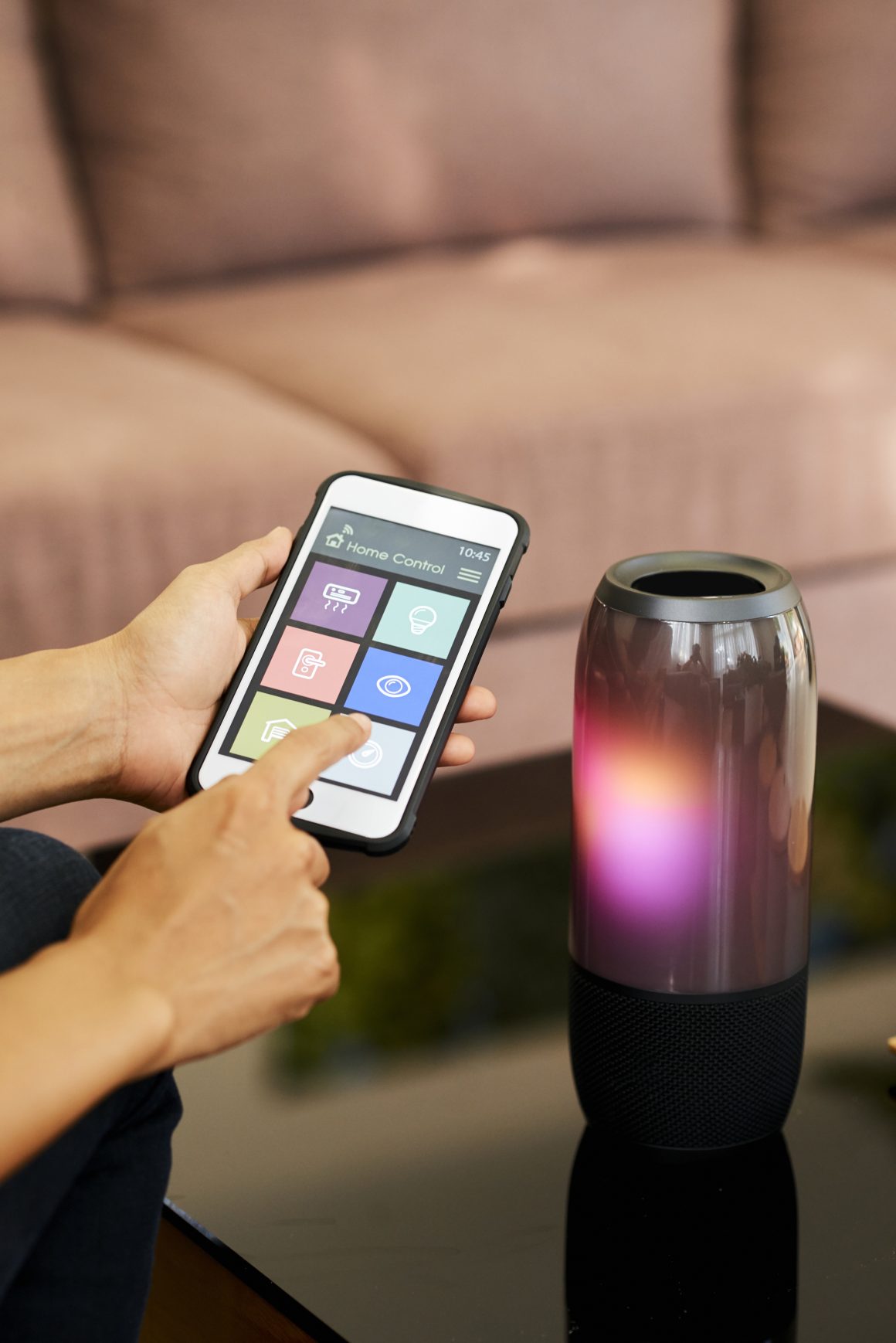 Personne tient un smartphone affichant une interface domotique, contrôlant la lumière ambiante à distance
