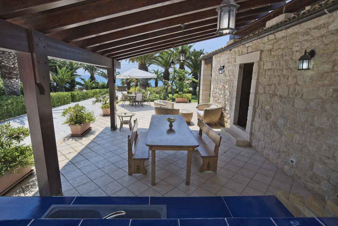 Terrasse en pierre couverte incluant table en bois et bancs avec vue sur jardin luxuriant