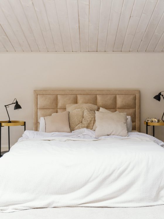 Chambre avec lit king-size blanc, têtes de lit beige, plantes vertes et lampes noires