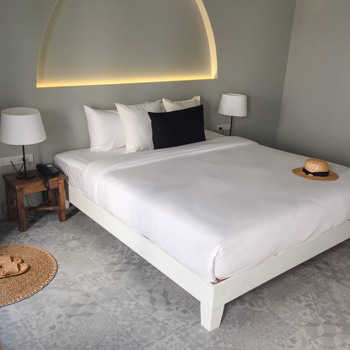 Lit double blanc, lampes, table en bois sol à motifs gris dans une chambre minimaliste