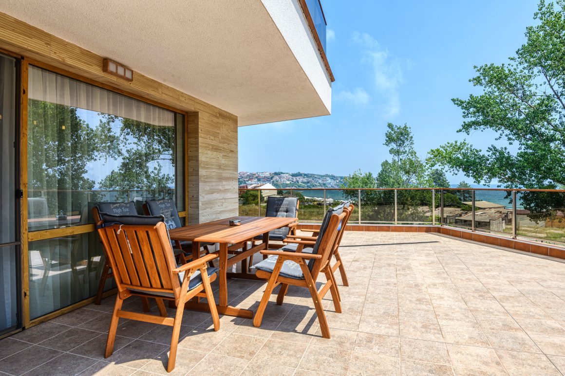Grande terrasse en travertin incluant table et chaises en bois avec vue sur mer
