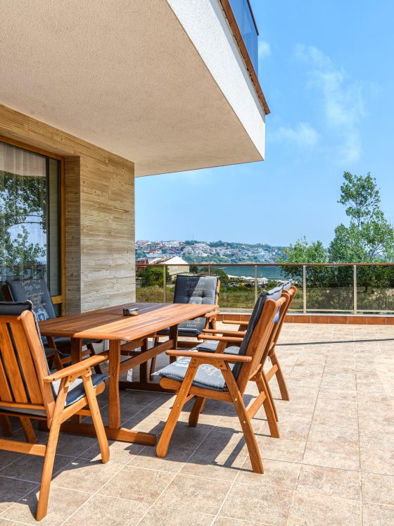 Grande terrasse en travertin incluant table et chaises en bois avec vue sur mer