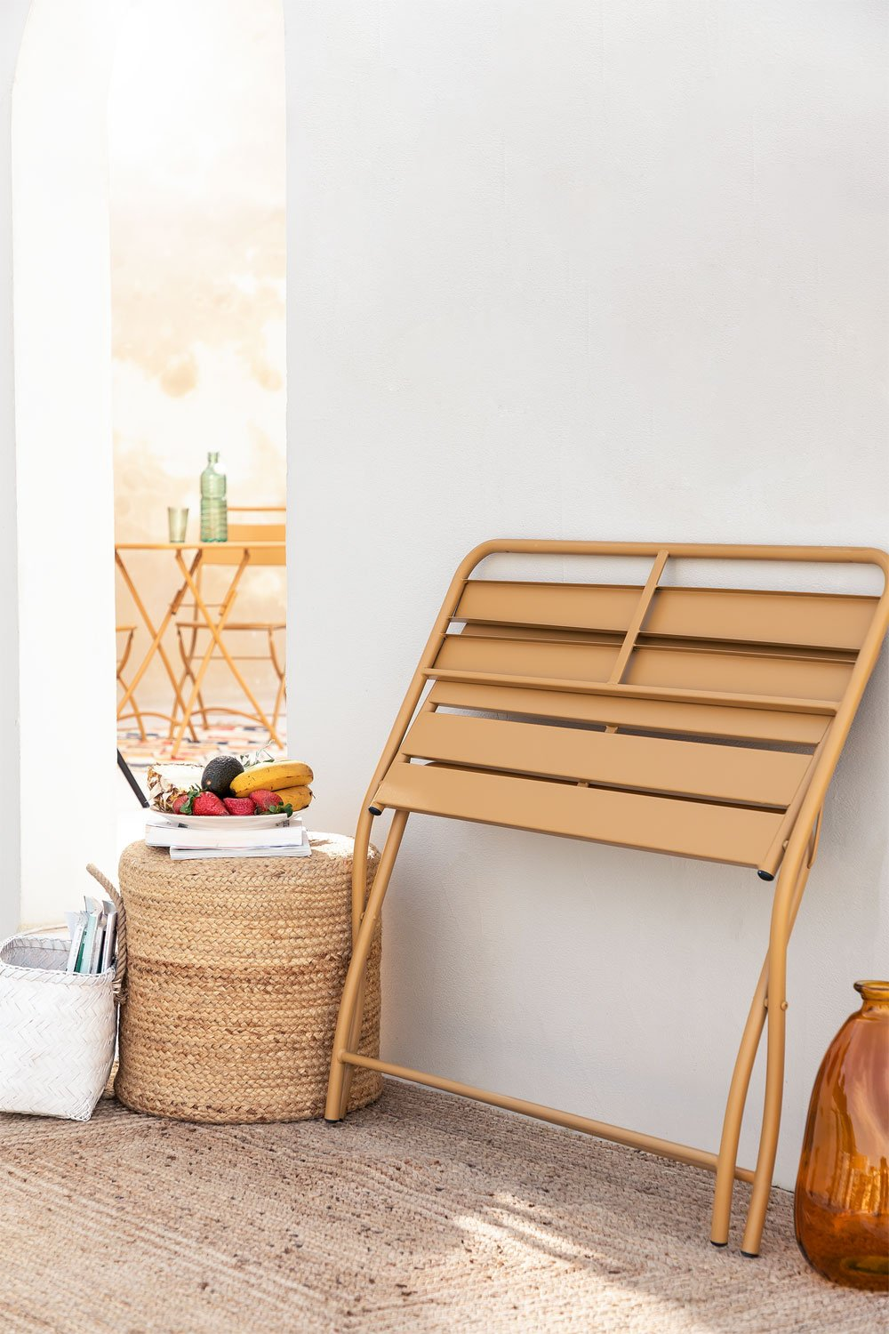 Banc de jardin pliant appuyée contre un mur avec panier tressé