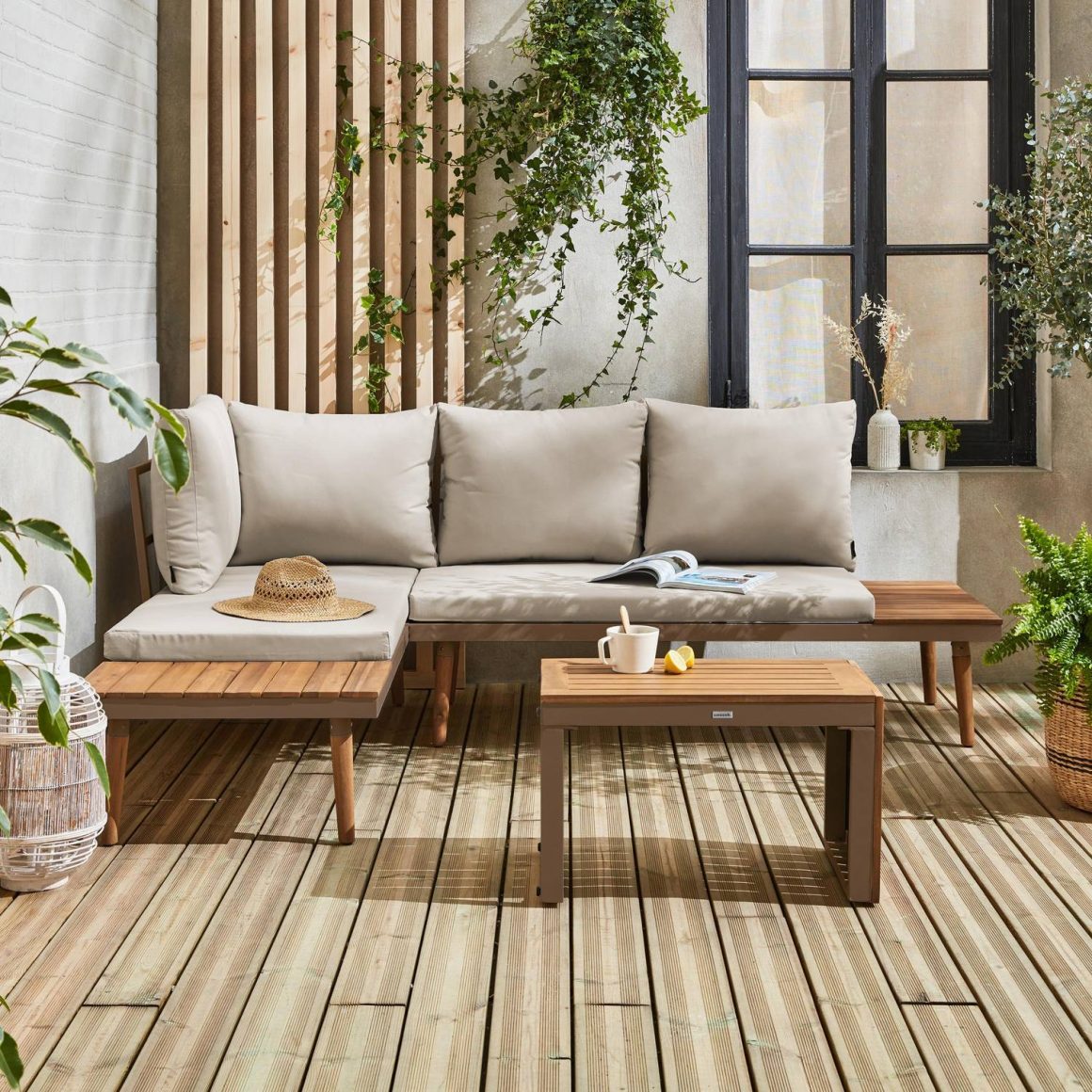 Coin détente extérieur avec canapé en bois, coussins beiges, plantes suspendues et table basse