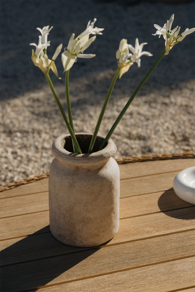 Table en bois avec vase en terre patiné incluant des fleurs blanches