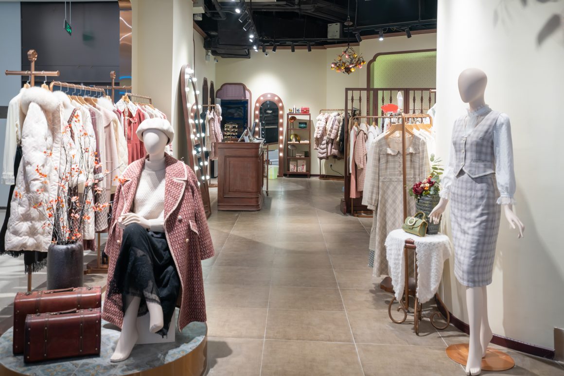 Boutique de mode féminine chic avec mannequins, miroirs , comptoir en bois et valises vintage
