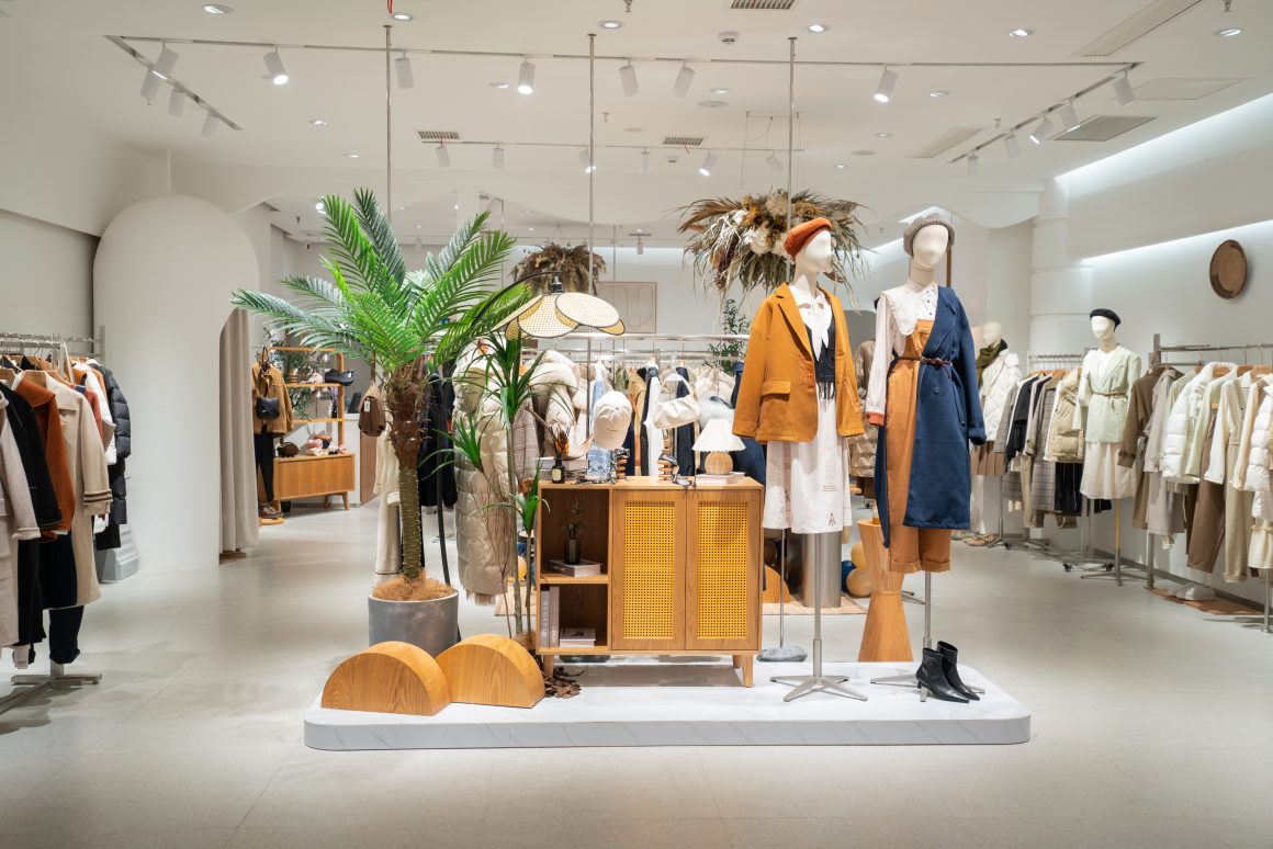 Vitrine élégante d'une boutique: mannequins stylés, plantes, meubles en bois, éclairage doux
