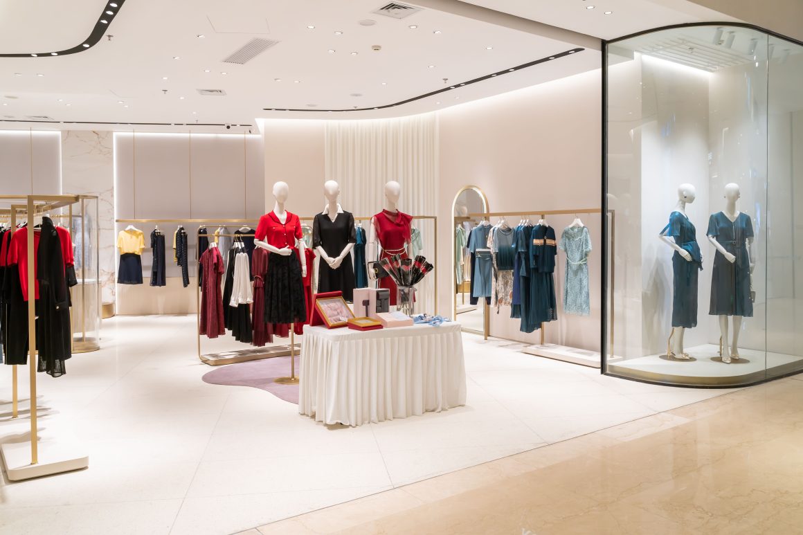 Boutique moderne avec murs blancs, mannequins, présentoirs vêtements, miroir et éclairage design