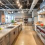 Aménagement cuisine professionnelle avec grand îlot central, équipements en inox, hottes et rangements fermés
