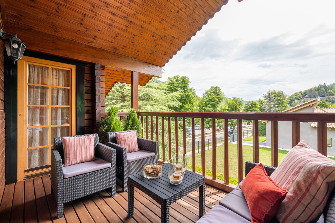 Balcon en bois chaleureux avec fauteuils tressés, coussins rayés et table basse