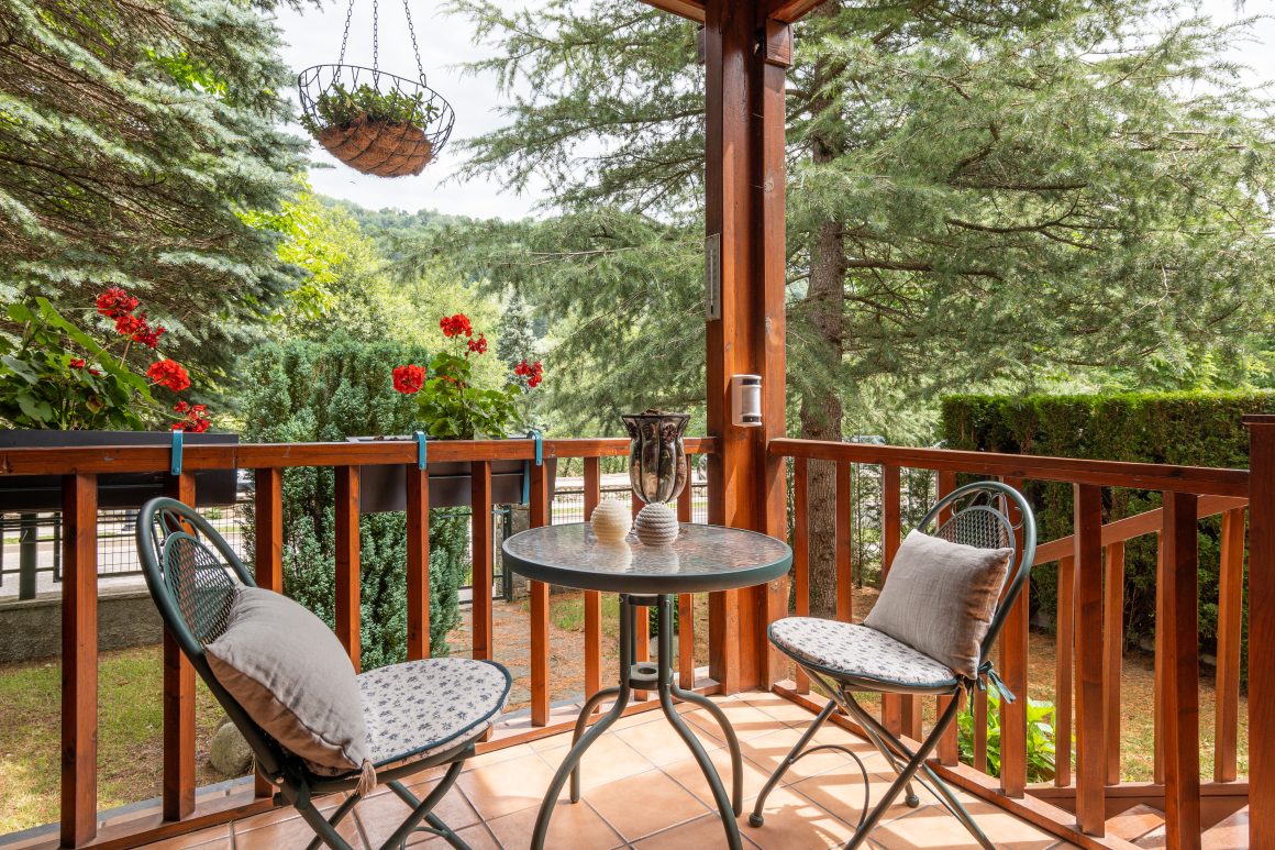Balcon en bois aménagé avec table ronde, deux chaises avec déco simple et planes suspendues