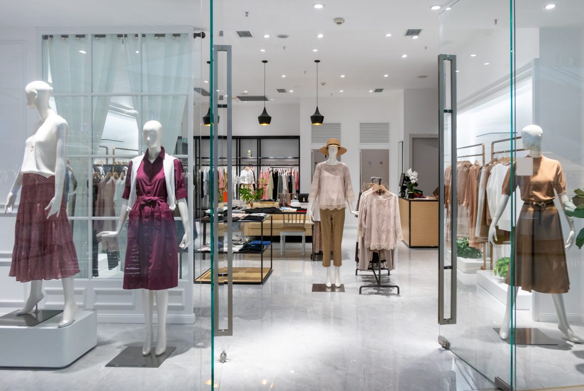 Agencement boutique avec vitrine, présentoirs vêtements, comptoir en bois et suspensions noires