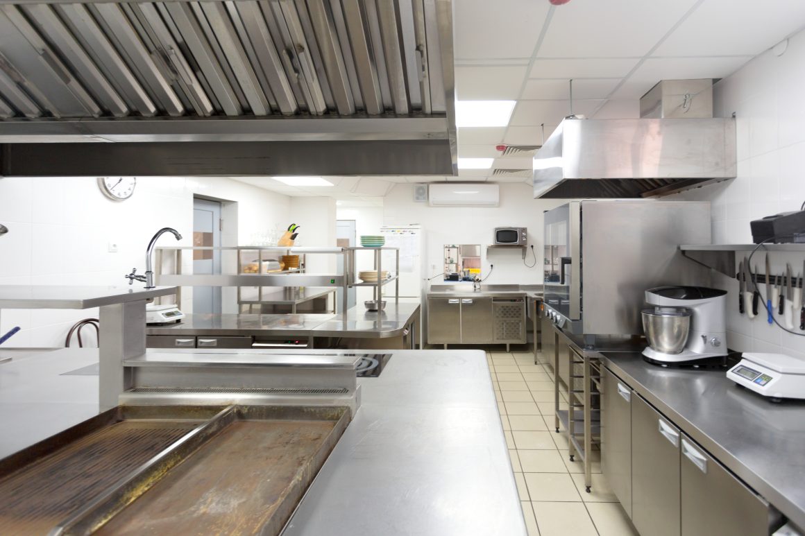 Aménagement cuisine professionnelle avec plans de travail en inox, hotte, équipement organisé et sol carrelé