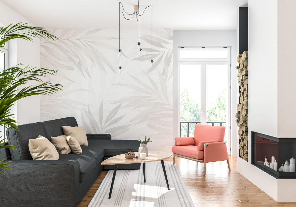 Canapé gris, fauteuil corail, mur habillé d’un papier peint à motifs végétaux, table basse et cheminée