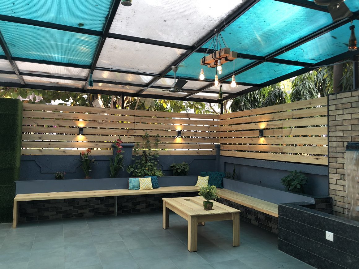 Coin détente extérieur avec bancs en bois, jardinières, table basse et toit translucide bleu