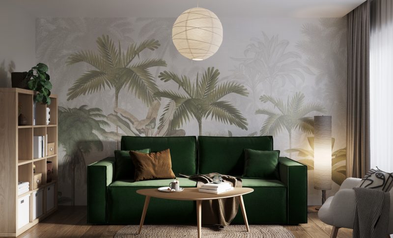 Habillage mur salon avec papier peint à motif tropical, canapé vert, table basse, étagères et lampe