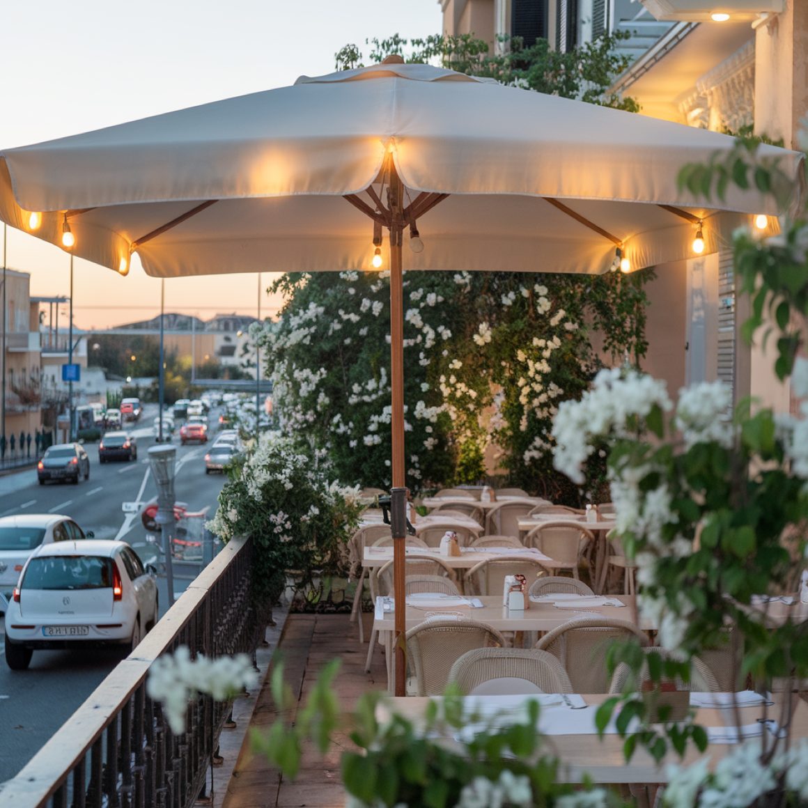 Terrasse d'un restaurant aménagée avec parasol éclairé, tables et chaises beiges