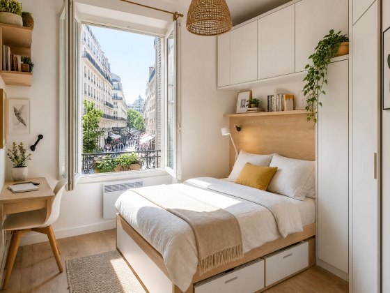 Petite chambre meublée avec bureau compact, chaise, lit avec rangement et étagères murales
