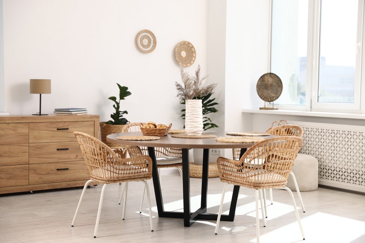 Salle à manger bohème incluant table ronde, chaises en rotin, buffet en bois et plantes