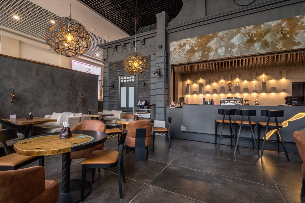 Restaurant aux tons gris incluant bar, tables en bois, chaises en cuir et suspensions