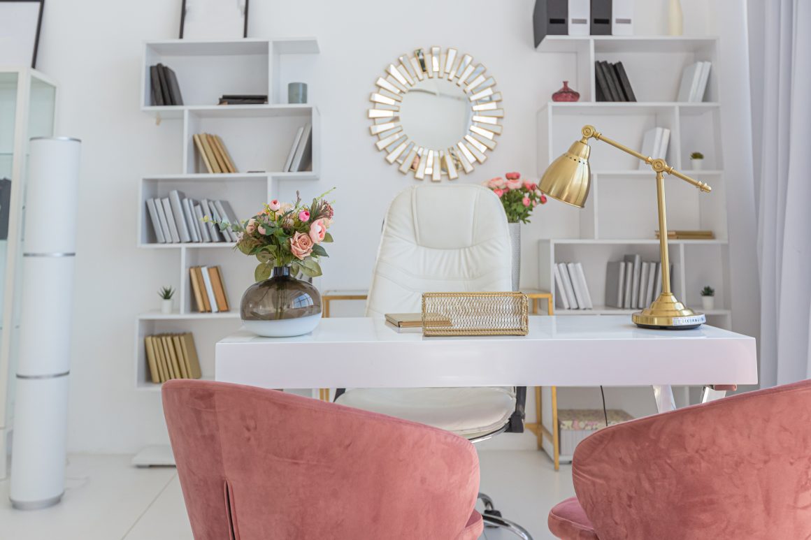 Bureau féminin : chaise blanche, lampes dorées, étagères minimalistes et fauteuils rose poudré