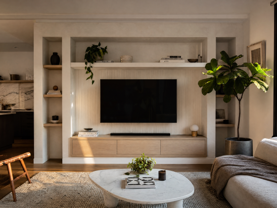 Salon aux tons neutres : TV encastrée dans un mur avec étagères, plantes, canapé et table basse en marbre