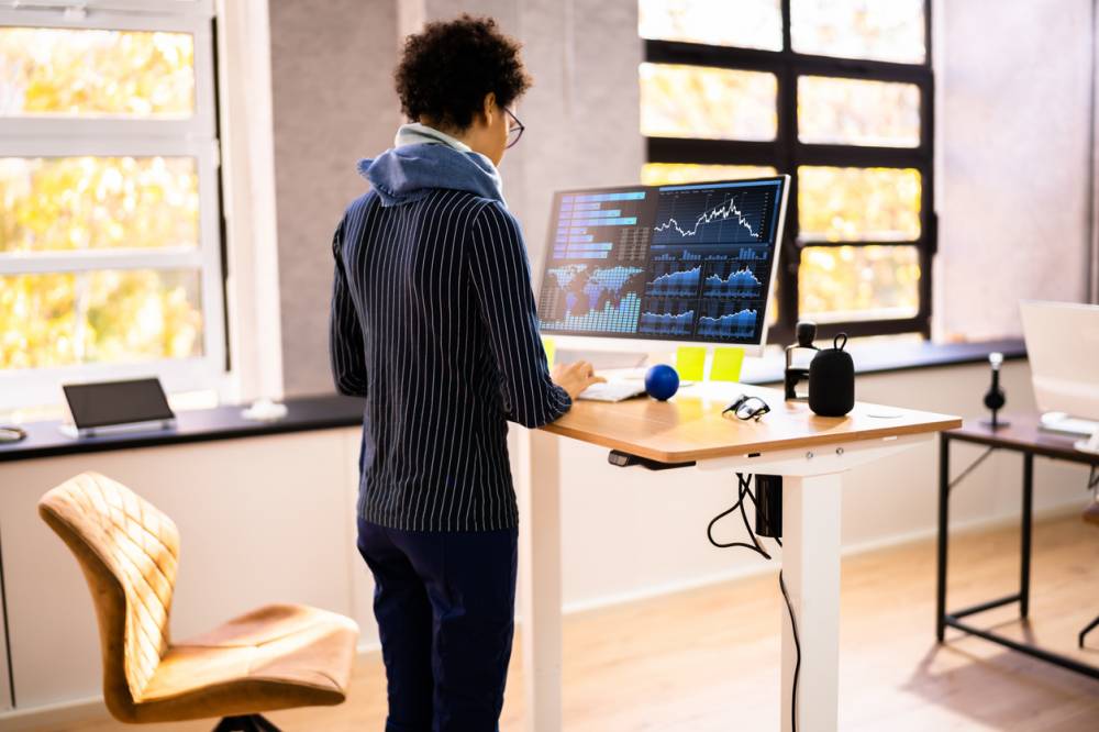 Personne debout à un bureau réglable dans un espace de travail moderne