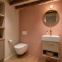Toilettes sans fenêtre avec un mur rose poudré, un meuble vasque beige et des poutres en bois