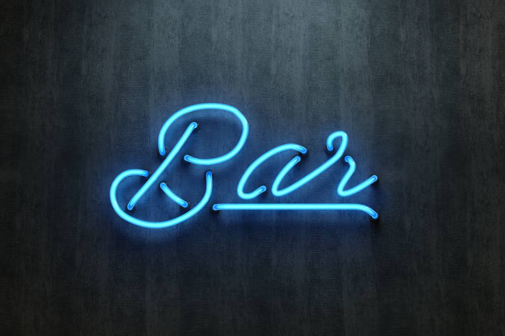 Néon bar bleu lumineux fixé sur un mur sombre texturé