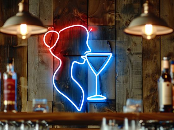 Gros plan sur un néon bar représentant une silhouette féminine et un verre à cocktail, fixé sur un mur en lattes de pin